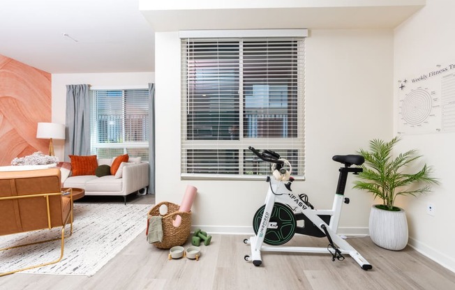 A room with a white exercise bike and a basket of toys.