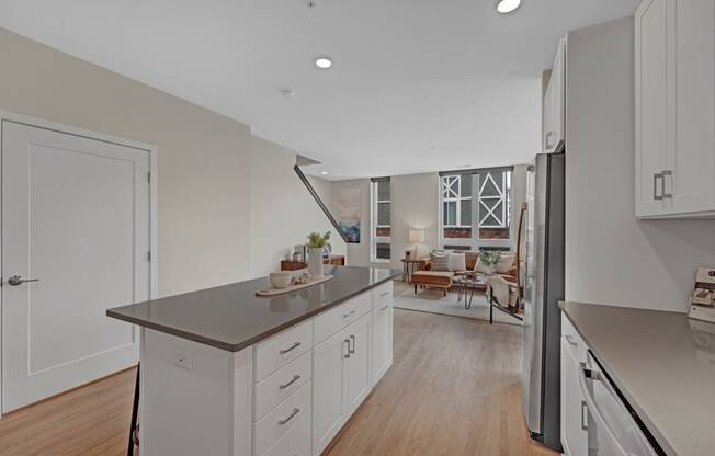 a kitchen with white cabinets and a counter top and a refrigerator
