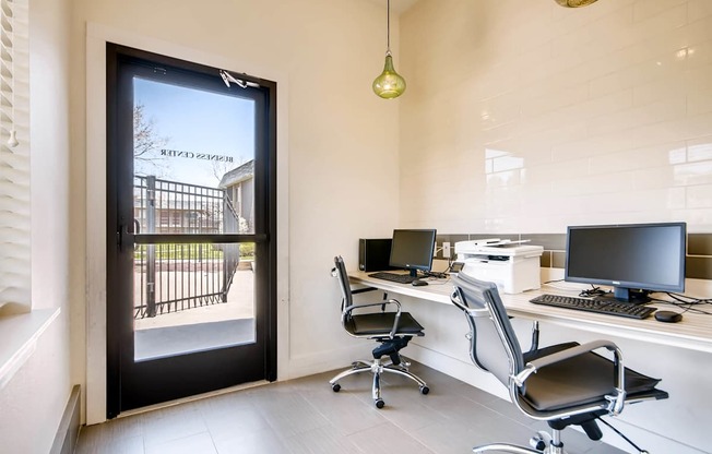 A modern office with a view of a gate and trees outside at Mountain Vista Apartments, Lakewood, CO