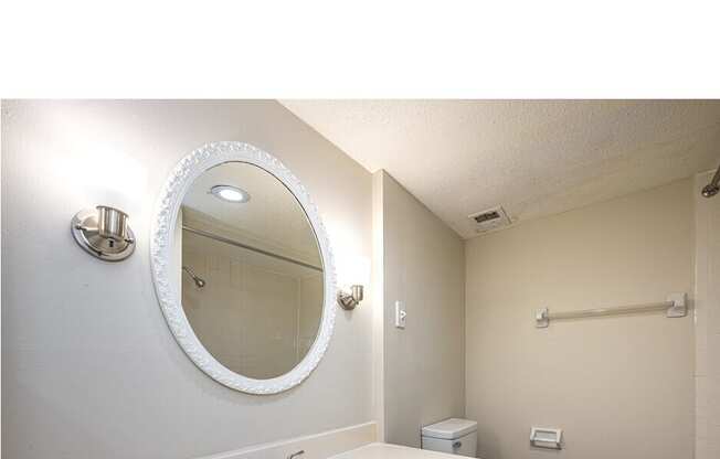 A bathroom with a white sink and a round mirror.