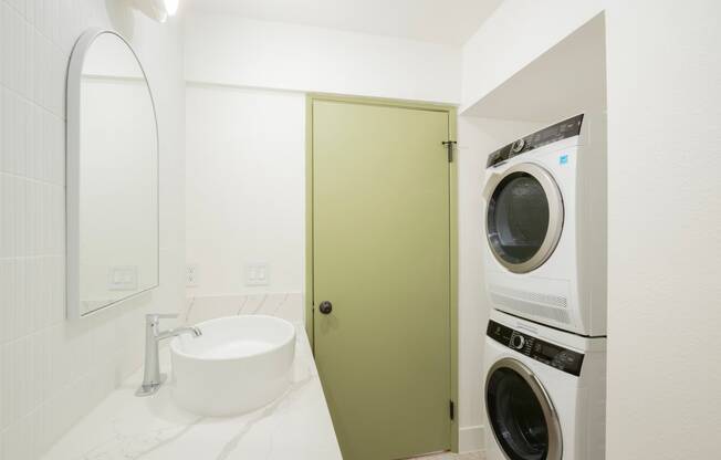 a white bathroom with a washer and dryer and a green door