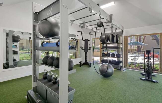 a gym with weights and other equipment on a green floor at Summerwood Apartments, Santa Clara