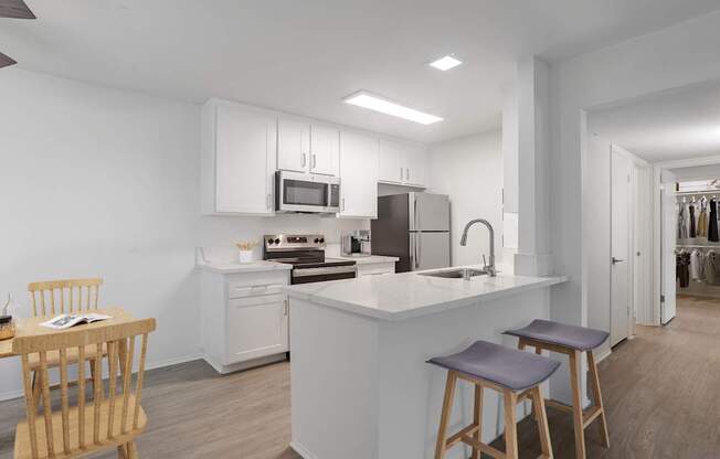 A modern kitchen with a white island and wooden stools.
