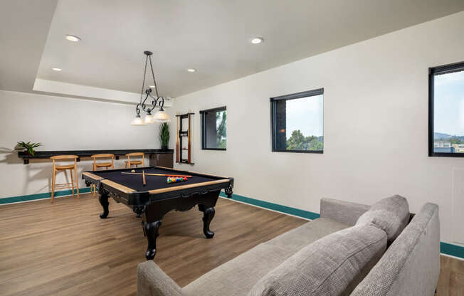 A pool table is in the middle of a room with a couch and a chair.
