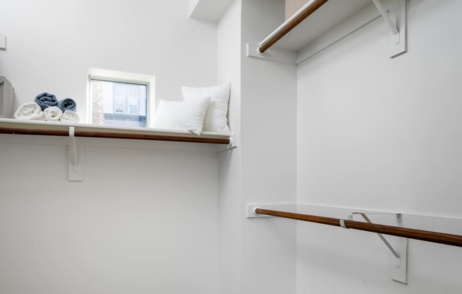 A white room with a window and a shelf with a box on top.
