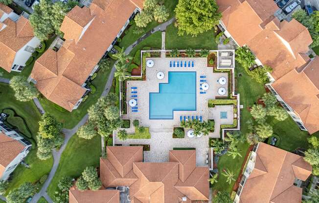 A bird's eye view of a residential area with a swimming pool and a small garden.