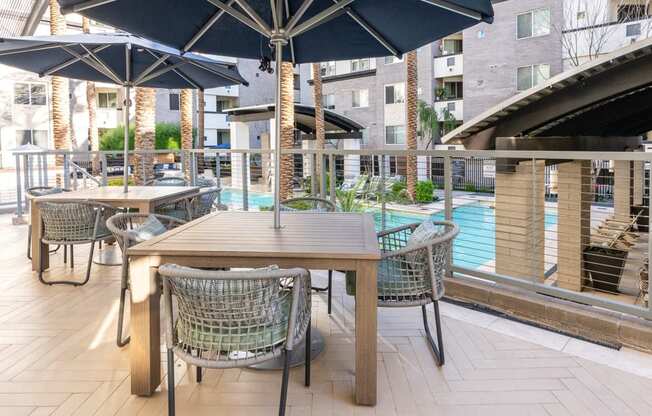 A table with chairs and umbrellas is set up on a patio.