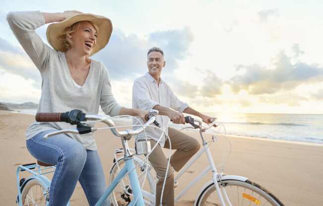a man and woman riding bikes on the beach