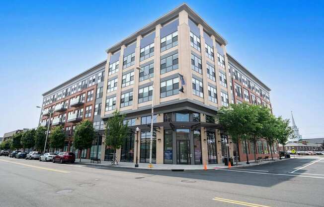 A modern multi-story building with a parking lot in front.