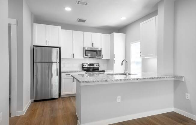 an empty kitchen with an island and stainless steel refrigerator