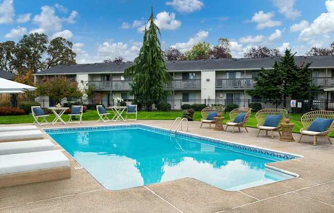 A swimming pool surrounded by lounge chairs and trees.
