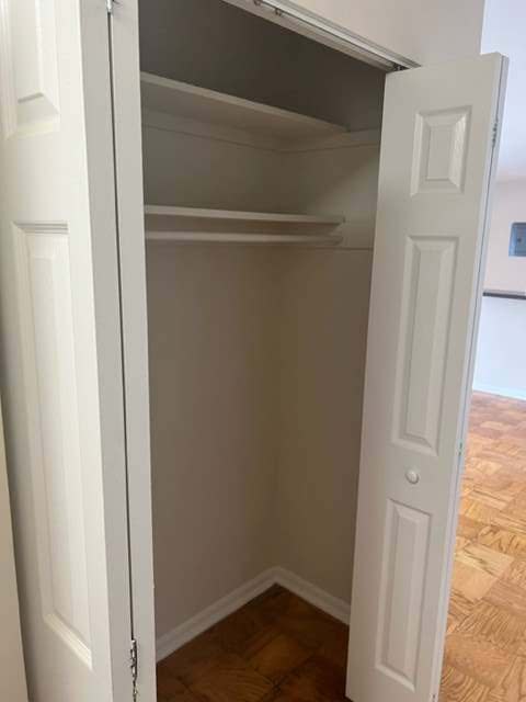 a walk in closet with white doors and a wooden floor
