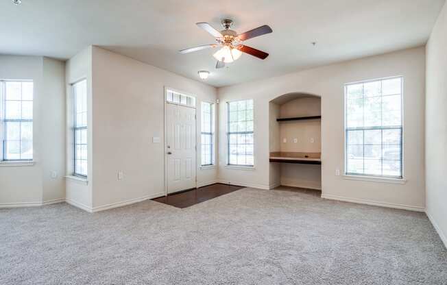 an empty living room with a ceiling fan