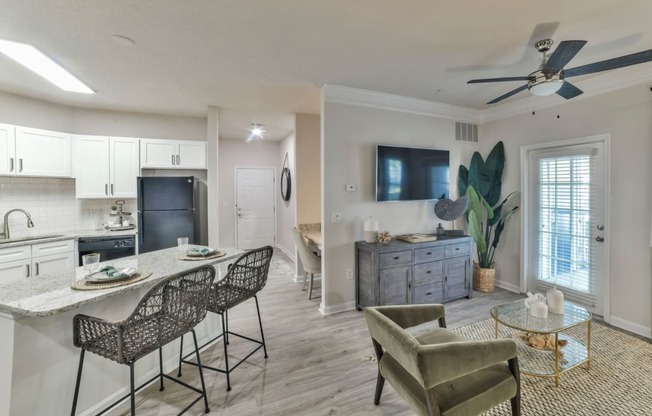 a living room with a kitchen and a ceiling fan