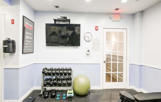 a gym with a television and weights on the floor