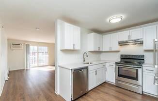an empty kitchen with white cabinets and stainless steel appliances