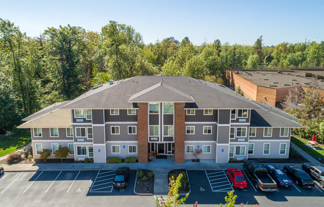 an aerial view of an apartment building with parking lot and trees