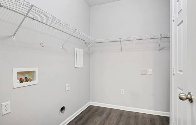 A white room with a door and a shelf with jars on it.