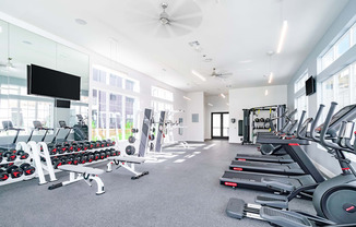 a spacious fitness room with cardio equipment and a flat screen tv
