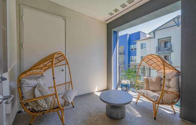 A room with two wicker chairs and a table.