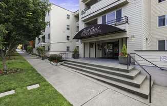 a large white building with a black awning showing property name at Hill Crest Apartment Homes, Seattle, 98126