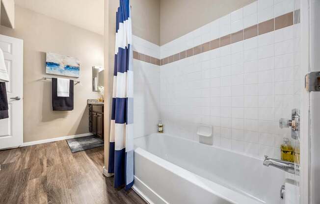 A bathroom with a white tub and a blue and white shower curtain.
