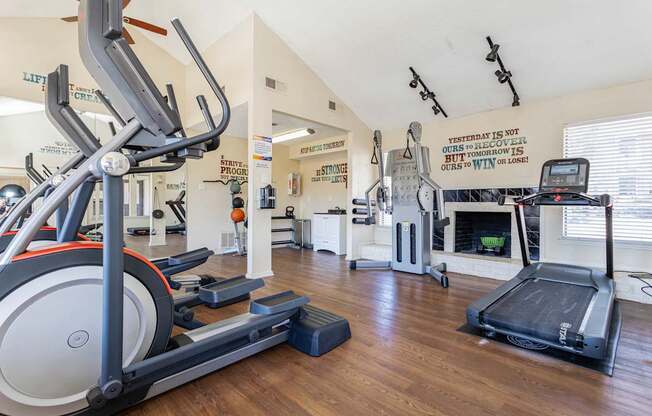 a gym with cardio equipment and a fireplace