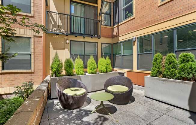 a patio with two chairs and a table in front of a building