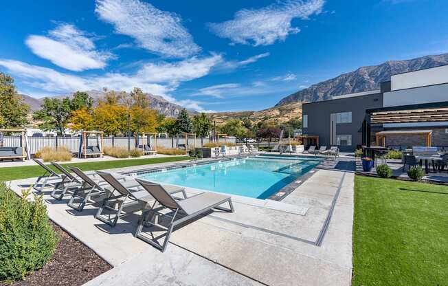 a swimming pool with patio furniture and a building with mountains in the background