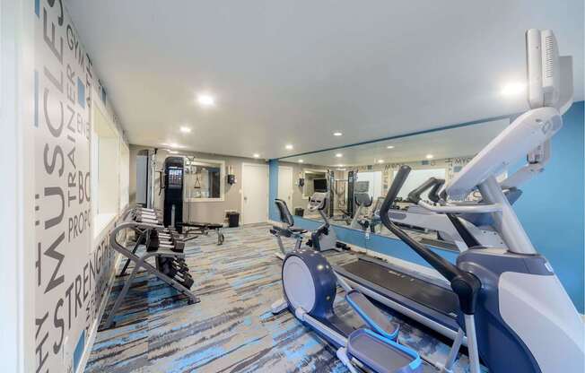 A gym with a row of treadmilers and a row of stationary bikes.