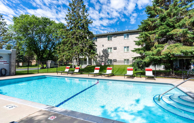 a swimming pool with chairs and a building in the background