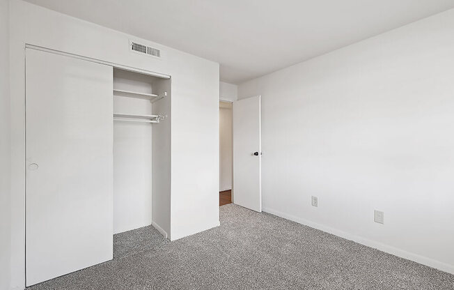 an empty bedroom with white walls and a closet