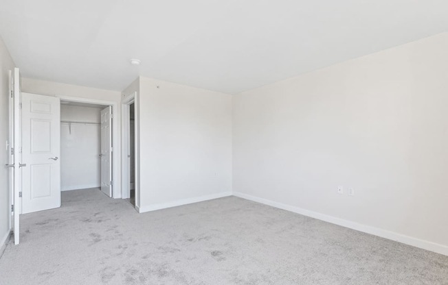 an empty bedroom with white walls and a door to a closet