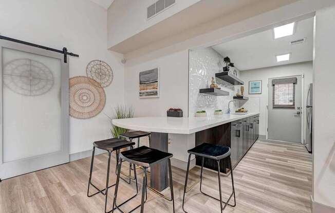 A kitchen with a white countertop and black barstools.