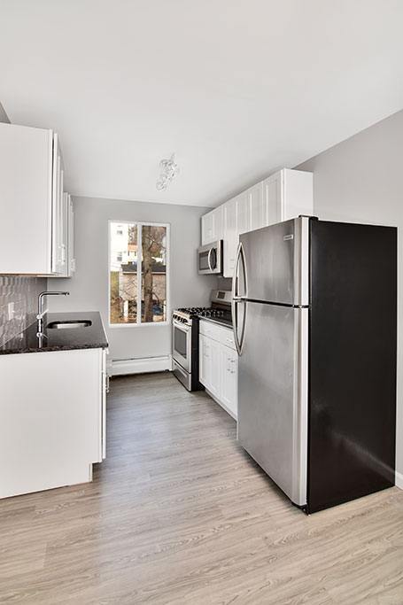 a kitchen with a black refrigerator and white cabinets at Springwood Gardens, Connecticut