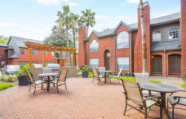 a patio with tables and chairs outside of a brick building