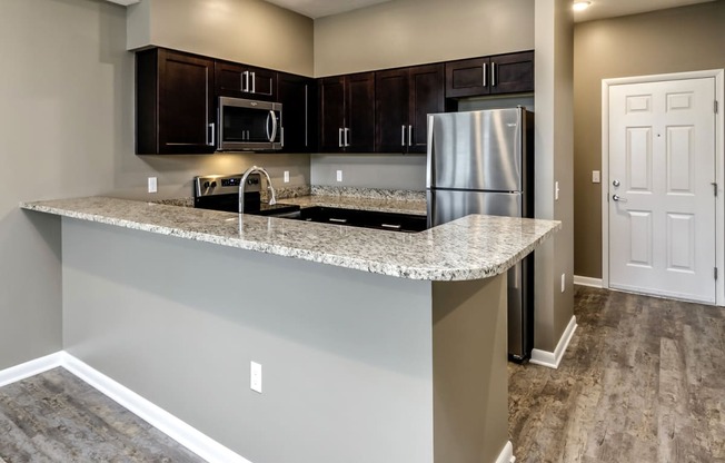 Large kitchen island with dark cabinets at The Apartments at Lux 96 in Papillion, NE
