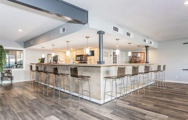 A bar area with a long counter and stools.