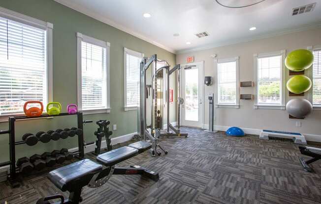 A gym with a variety of equipment including weights, a bench, and a ball.