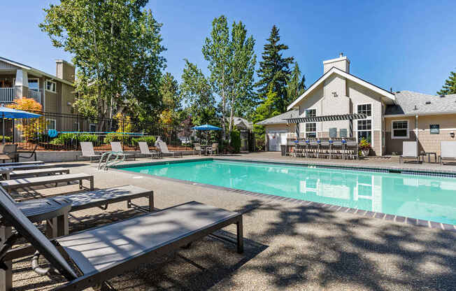 A pool with a bench and a house in the background.