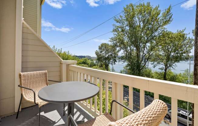 a table and two chairs sit on a balcony with a view of the water