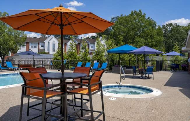 a table with chairs and an umbrella next to a pool