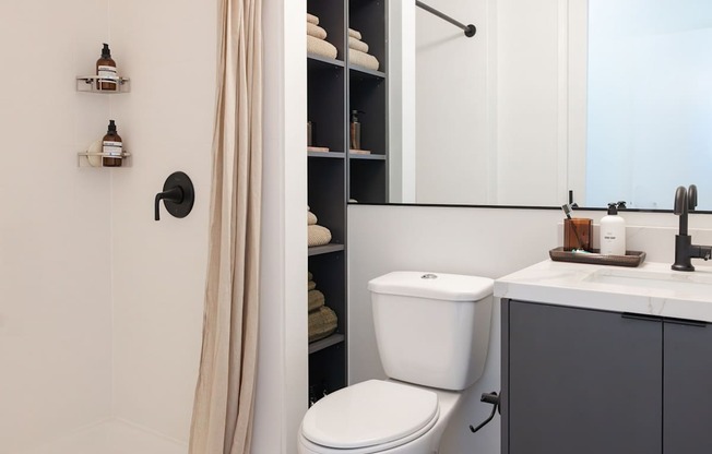 A white toilet sits next to a bathroom sink with a mirror above it at Skylar At Sunset Apartments, California, 90027