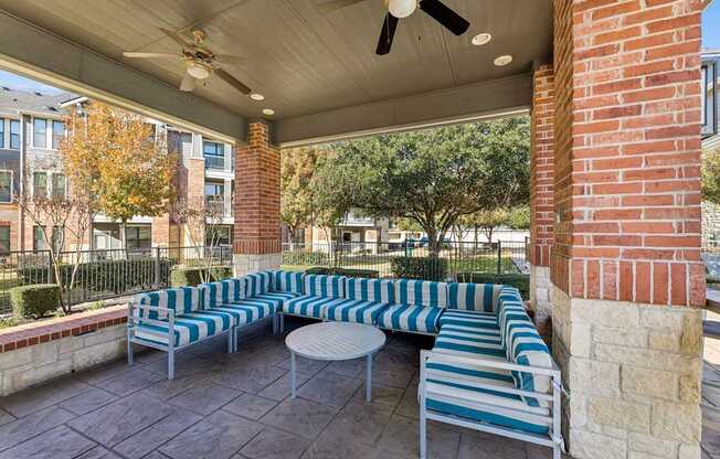 A patio with a striped couch and a ceiling fan.