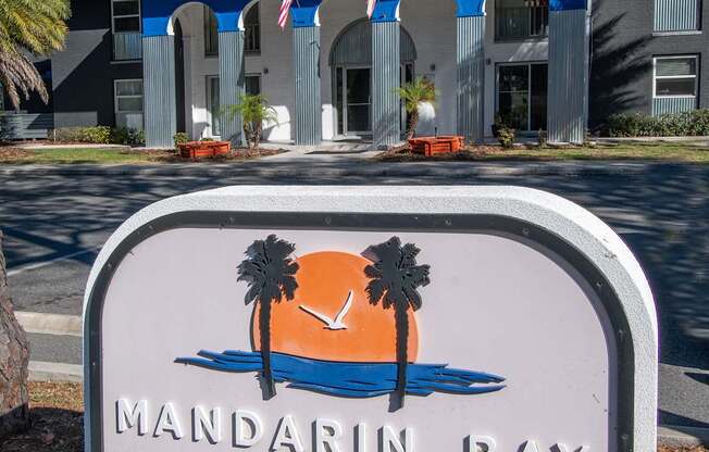 A sign for Mandarin Bay Luxury Apartments sits in front of a building.