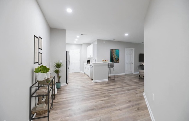 a living room and kitchen with white walls and a wooden floor