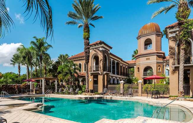 Palm-lined pool with shaded seating and arched building backdrops