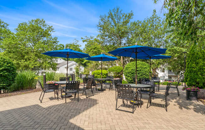 A patio with tables and chairs under blue umbrellas.