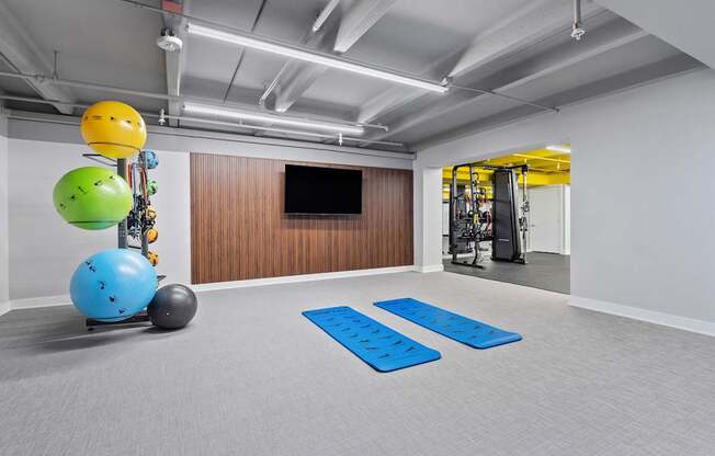 A room with a blue mat on the floor and a TV on the wall.
