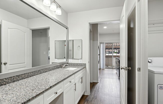A bathroom with a granite countertop and white cabinets.